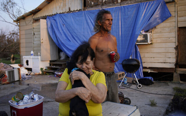 Yvonne Lacobon hugs a dog beside Tommy Williams at Williams' home damaged by Hurricane Ida, in Dulac, La., Sept. 4, 2021. (John Locher/AP)