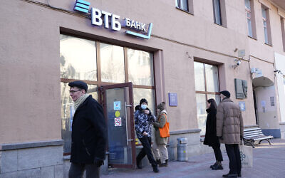 People stand in line to withdraw money from an ATM of VTB Bank in downtown Moscow, Russia, Monday, Feb. 28, 2022. (AP Photo/Pavel Golovkin)