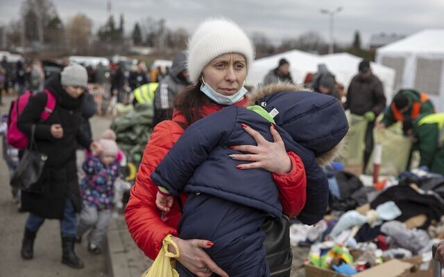 A woman carries her child as she arrives at the Medyka border crossing after fleeing from Ukraine, in Poland, February 28, 2022. (AP Photo/Visar Kryeziu)