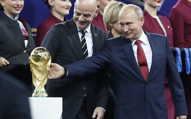Russian President Vladimir Putin touches the World Cup trophy as FIFA President Gianni Infantino stands beside him, at the end of the final match between France and Croatia at the 2018 soccer World Cup in the Luzhniki Stadium in Moscow, Russia, on July 15, 2018. (AP Photo/Petr David Josek, File)