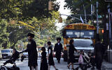 In this September 20, 2013 file photo, children and adults cross a street in front of a school bus in Borough Park, a neighborhood in the Brooklyn borough of New York that is home to many ultra-Orthodox Jewish families. (AP Photo/Bebeto Matthews, File)