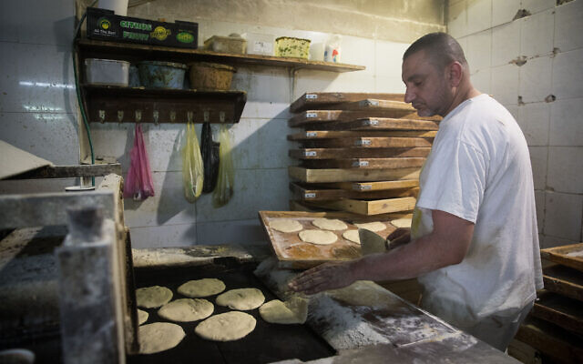 A man prepares pita bread at a bakery at the Mahane Yehuda Market in Jerusalem on April 16, 2020 (Yonatan Sindel/Flash90)