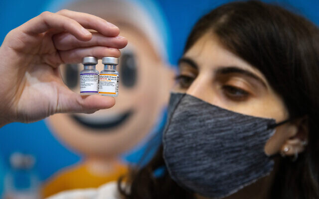 A healthcare worker holds doses of the coronavirus vaccine in Jerusalem on November 23, 2021. (Olivier Fitoussi/Flash90)