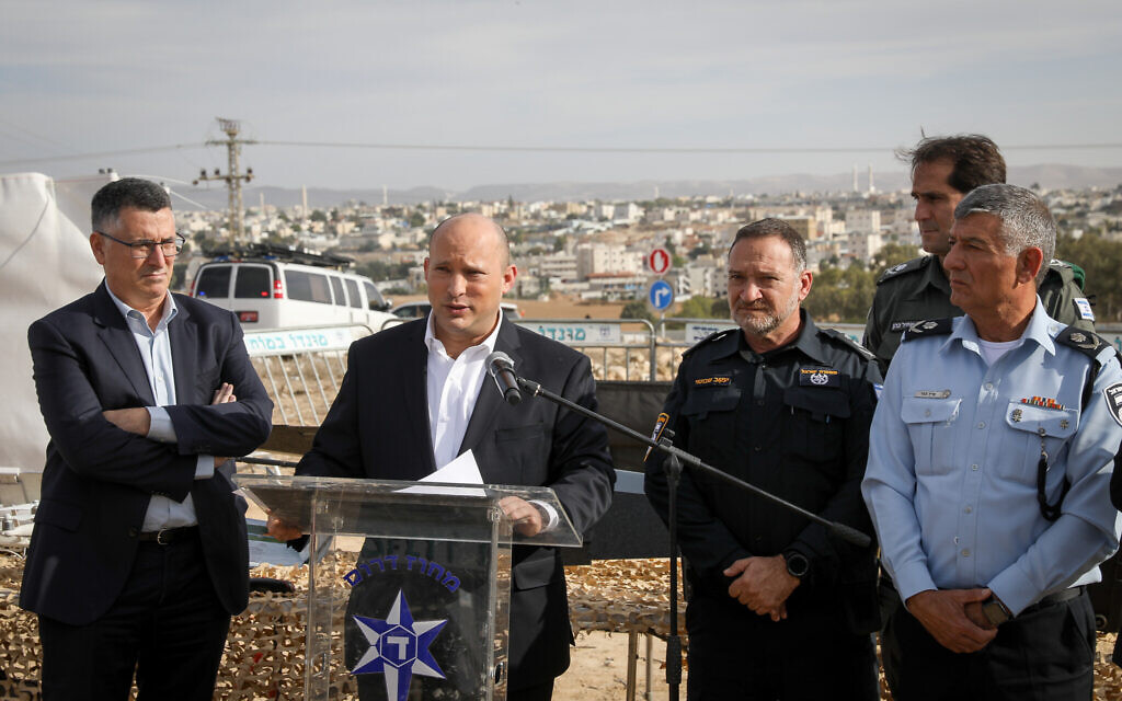 Prime Minister Naftali Bennett speaks alongside police officials and Justice Minister Gideon Sa'ar, left, during a visit to Rahat on December 6, 2021. (Noam Revkin Fenton/Flash90)