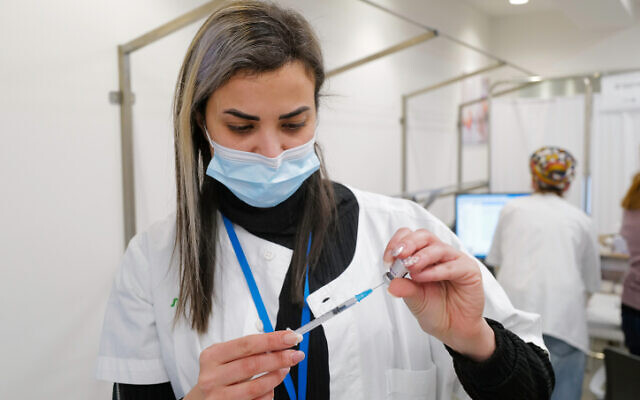 A health worker prepares to give a dose of the COVID-19 vaccine at a Clalit Health Services center in Katzrin, Golan Heights, January 9, 2022. (Michael Giladi/Flash90)