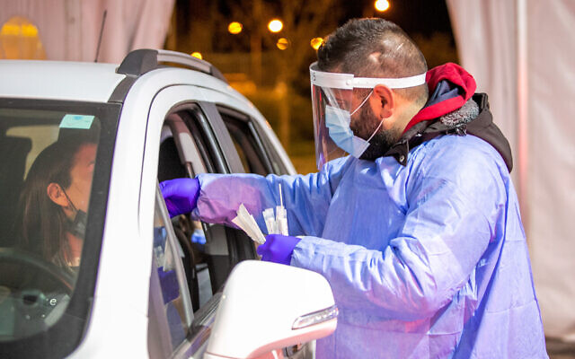 Health care worker takes swab samples from Israelis at a covid-19 drive through testing complex in Modi'in, February 1, 2022. (Yossi Aloni/Flash90)