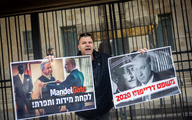Supporters of former Israeli Prime Minister Benjamin Netanyahu protest outside his trial at the District Court in Jerusalem, February 7, 2022. The placards (left) blame former attorney general Avichai Mandelblit for fabricating the charges and (right) compare the case to the Dreyfus affair. (Yonatan Sindel/Flash90)