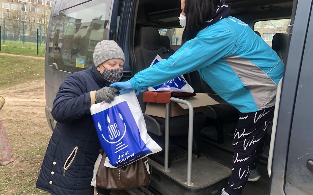 A Joint Distribution Committee worker hands food and PPE to a Jewish client in Kharkiv, Ukraine (courtesy JDC) .