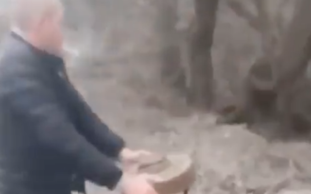 A Ukrainian man removes a mine from a road in Berdyansk, on February 27, 2022. (Screenshot/YouTube)