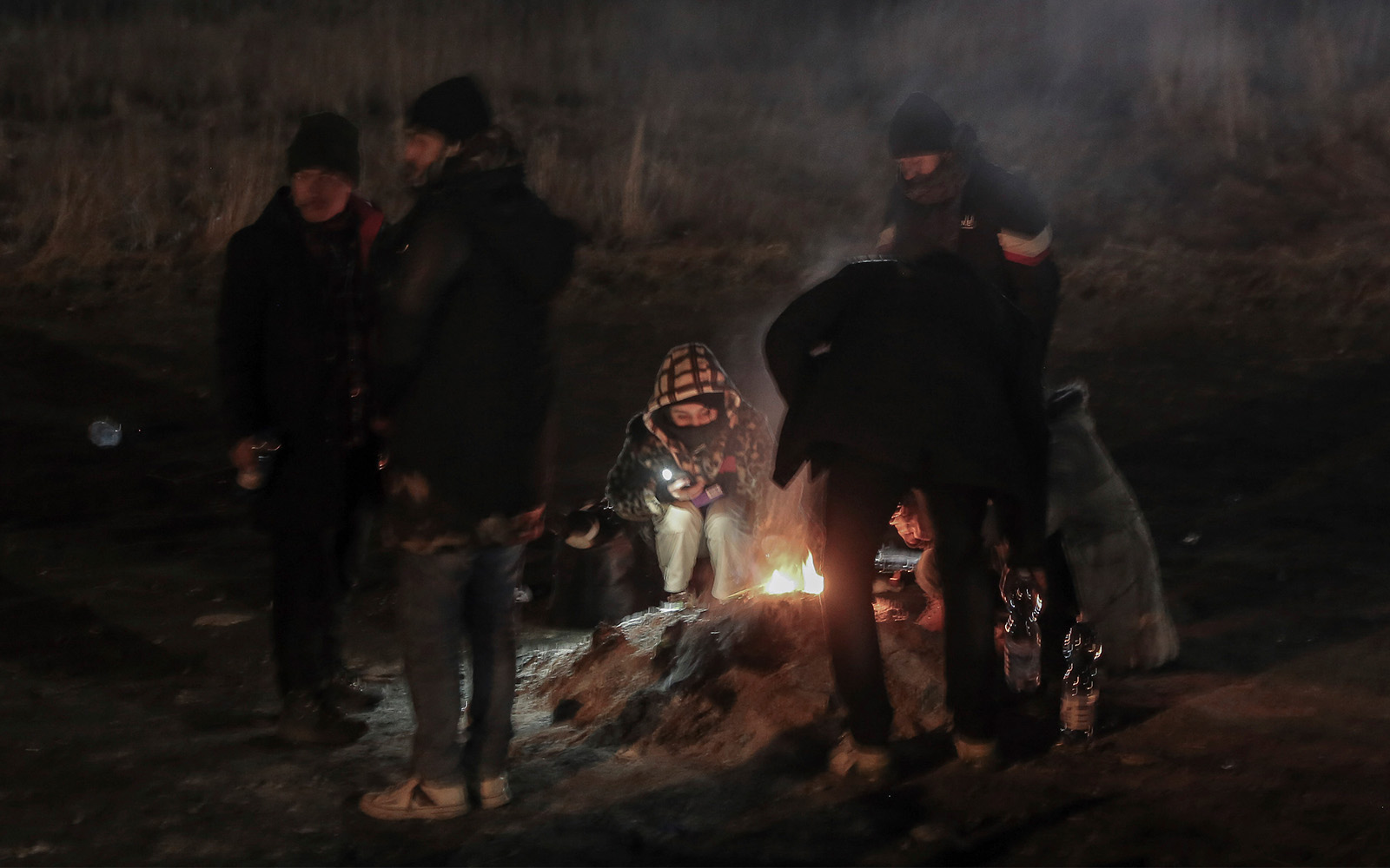 Students gather around campfire to warm themself at the Medyka border crossing after fleeing from the Ukraine, in Poland, February 28, 2022. (AP Photo/Visar Kryeziu)