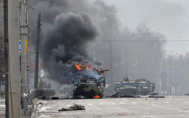 A Russian military vehicle burns next to a soldier's body in Kharkiv, Ukraine, February 27, 2022. (Sergey Bobok/AFP)
