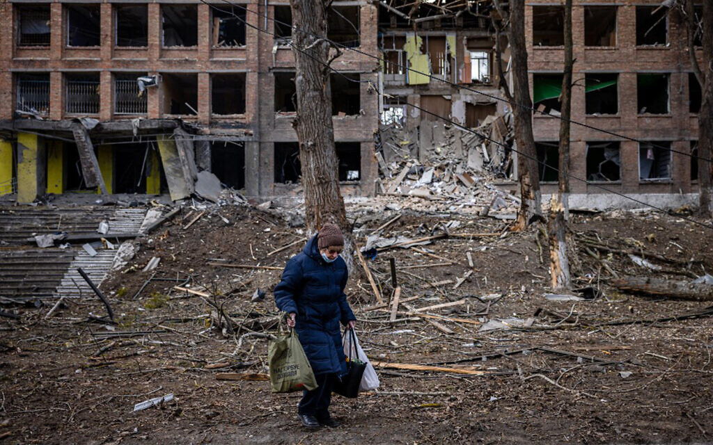 A woman walks in front of a destroyed building after a Russian missile attack in the town of Vasylkiv, near Kyiv, on February 27, 2022. (Dimitar Dilkoff/AFP)