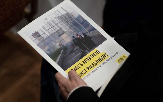 A journalist holds a copy of Amnesty International's report 'Israel's Apartheid Against Palestinians,' in Jerusalem, February 1, 2022. (Maya Alleruzzo/AP)