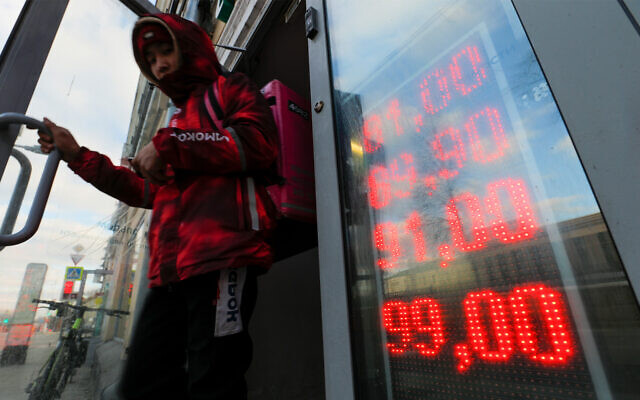 A man leaves an exchange office with screen showing the currency exchange rates of US dollar and euro to Russian Rubles in Moscow, Russia, February 24, 2022. (AP Photo/Alexander Zemlianichenko Jr)