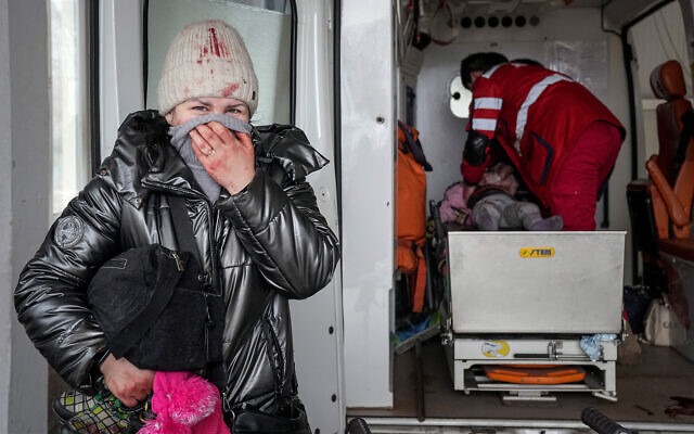 A woman reacts as paramedics perform CPR on a girl who was injured during shelling, at a city hospital of Mariupol, eastern Ukraine, February 27, 2022. The girl did not survive. (AP Photo/Evgeniy Maloletka)