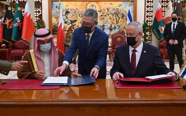 Defense official Zohar Palti, center, presents Bahraini Minister of Defense Affairs Abdullah Bin Hassan Al Nuaimi with a memorandum of understanding that had just been signed by Defense Minister Benny Gantz at the Bahraini defense headquarters, on February 3, 2022. (Ariel Hermoni/Defense Ministry)