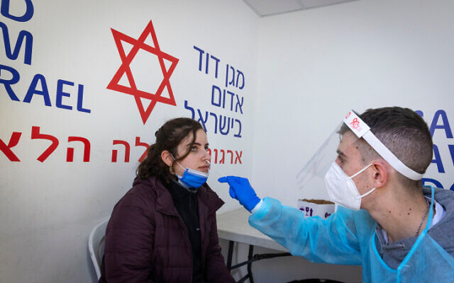 A health worker takes a sample at a testing center in Jerusalem, on January 09, 2022. (Olivier Fitoussi/Flash90)