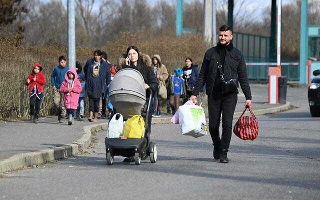 A Ukrainian refugee family and other Ukrainians fleeing their country arrive at the Ukrainian-Hungarian border crossing in Tiszabecs, on February 27, 2022. (Attila Kisbenedek/AFP)
