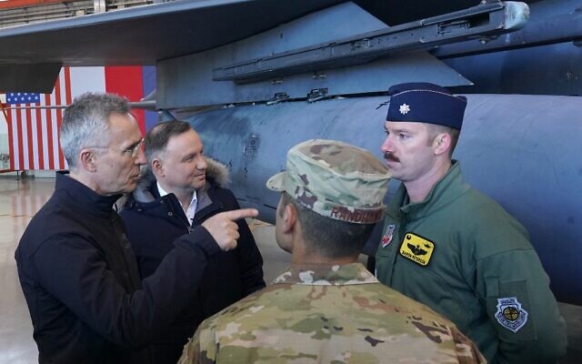 NATO Secretary General Jens Stoltenberg (L) and Polish President Andrzej Duda speak with military personnel on March 1, 2022 at the military air base in Lask, Poland. (JANEK SKARZYNSKI / AFP)