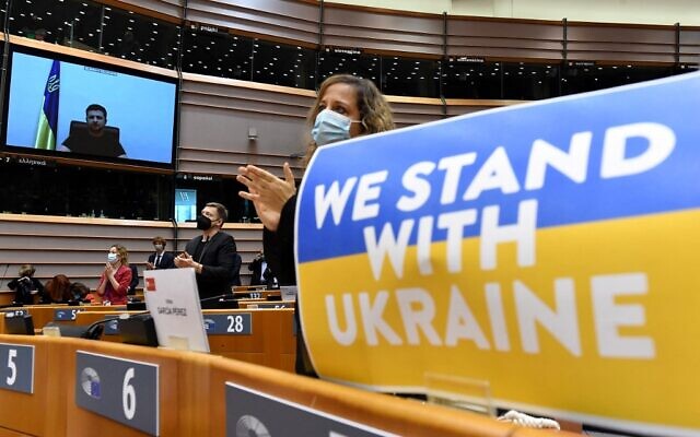 Members of the European Parliament applaud Ukrainian President Volodymyr Zelensky who appears on a screen as he speaks in a video conference during a special plenary session of the European Parliament focused on the Russian invasion of Ukraine at the EU headquarters in Brussels, on March 01, 2022. (JOHN THYS / AFP)