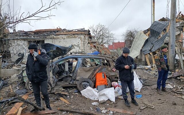 Three men stand in the rubble in Zhytomyr on March 2, 2022, following a Russian bombing the day before. (Emmanuel DUPARCQ / AFP)