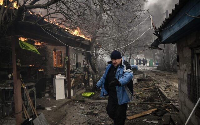 A man walks next to a house burning after being shelled in the city of Irpin, outside Kyiv, on March 4, 2022. (Aris Messinis/AFP)