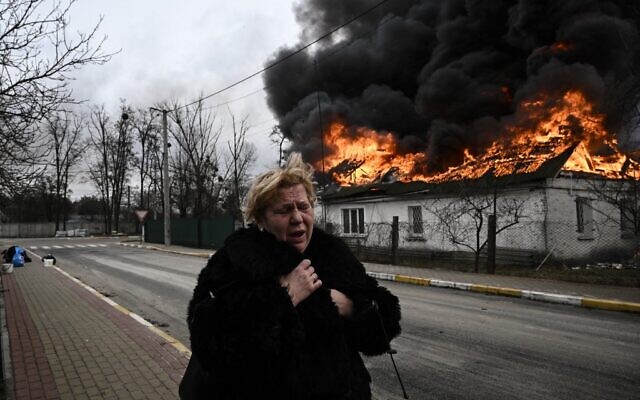 A woman reacts as she stands in front of a house burning after being shelled in the city of Irpin, outside Kyiv, on March 4, 2022. (Aris Messinis/AFP)