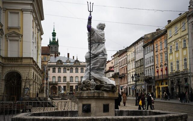 Pedestrians walk past a wrapped statue next to the Archcathedral Basilica of the Assumption of the Blessed Virgin Mary also known as Latin Cathedral in Lviv western Ukraine, on March 5, 2022. (Daniel LEAL / AFP)