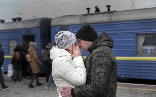 A couple embrace as they stand in front of an evacuation train at the central train station in Odesa on March 6, 2022. (BULENT KILIC / AFP)