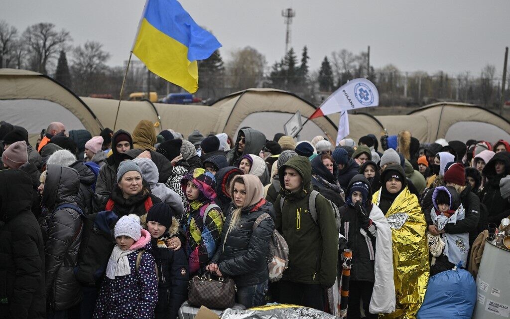 Hundreds of refugees stand in line as they wait to be transferred after crossing the Ukrainian border into Poland, at the Medyka border crossing in Poland, on March 7, 2022 (Louisa GOULIAMAKI / AFP)
