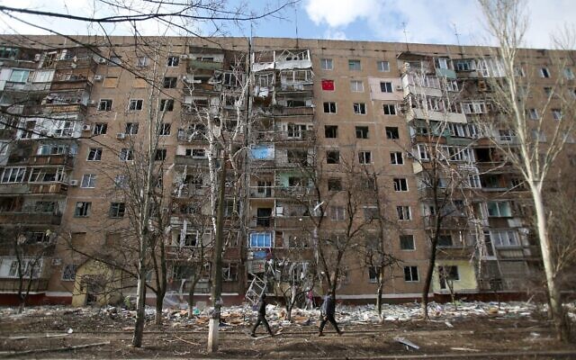 People walk in front of a multi-story building that was badly damaged as a result of Russian missile explosion after it was shot down over the city by Ukrainian air defense on March 6, in Kramatorsk on March 7, 2022. (Anatolii Stepanov / AFP)