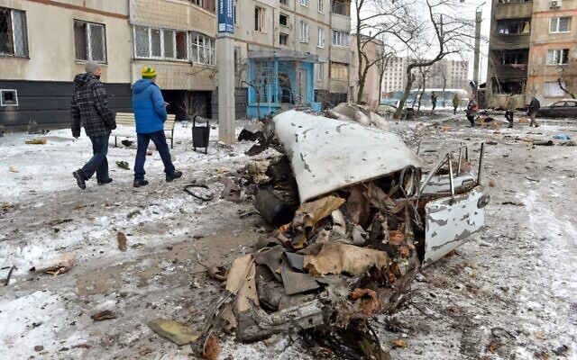 Pedestrians walk past a destroyed car following a shelling in Ukraine's second-biggest city of Kharkiv on March 7, 2022 (Sergey BOBOK / AFP)