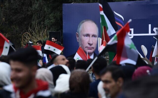 Syrian students wave the Syrian, Russian and Palestinian flags under a billboard bearing the portrait of Russian President Vladimir Putin during a demonstration in support of Russia, following the Russian invasion of Ukraine, at the Aleppo University campus in the Syrian city, March 10, 2022. (Photo by AFP)