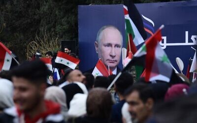 Syrian students wave the Syrian, Russian and Palestinian flags under a billboard bearing the portrait of Russian President Vladimir Putin during a demonstration in support of Russia, following the Russian invasion of Ukraine, at the Aleppo University campus in the Syrian city, on March 10, 2022. (AFP)