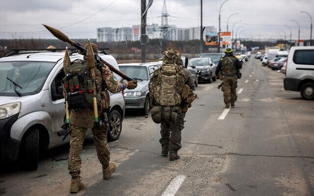 Ukrainian servicemen carry rocket-propelled grenades and sniper rifles as they walk towards the city of Irpin, northwest of Kyiv, on March 13, 2022. (Dimitar Dilkoff/AFP)