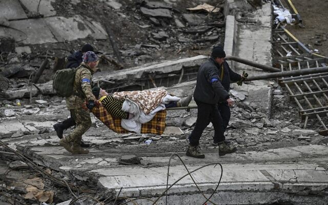 Ukrainian servicemen evacuate an elderly woman on a stretcher from the city of Irpin on March 13, 2022. (Aris Messinis / AFP)