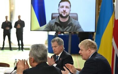 Britain's Prime Minister Boris Johnson and attendees applaud after Ukraine's President Volodymyr Zelensky addressed them by video link during a meeting of the leaders of the the Joint Expeditionary Force (JEF), a coalition of 10 states focused on security in northern Europe, at Lancaster House, in London on March 15, 2022. (JUSTIN TALLIS / POOL / AFP)