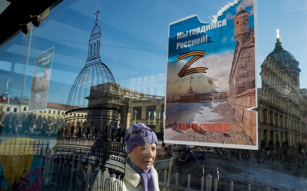 A woman walks past posters bearing the letter 'Z' in the colors of the ribbon of Saint George, which has become a symbol of support for Russian military action in Ukraine, and reading 'We are proud of Russia! We are not ashamed!' at a bus stop on Nevsky Prospekt in central Saint Petersburg on March 15, 2022. (AFP)