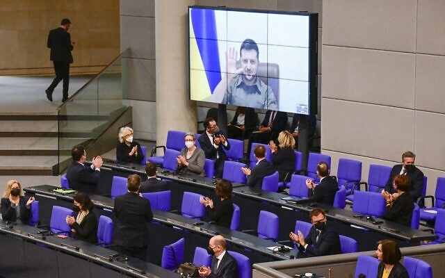 Members of the German government, among them Chancellor Olaf Scholz (bottom center), applaud as Ukrainian President Volodymyr Zelensky appears on a screen to address via videolink the German lower house of parliament, at the Bundestag in Berlin, March 17, 2022. (Tobias Schwarz/AFP)
