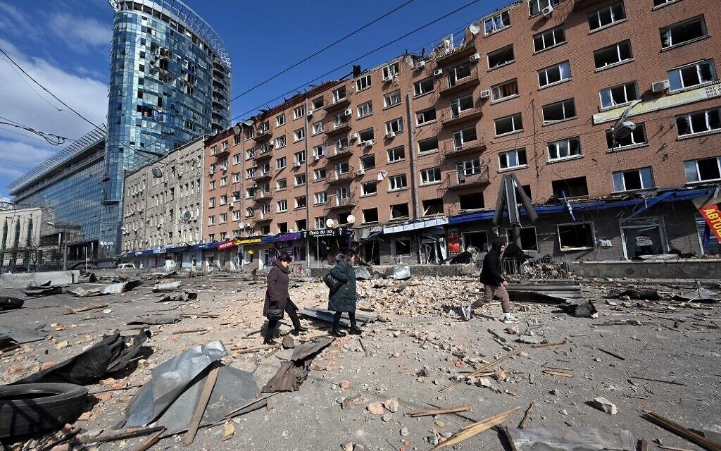 People walk by a building damaged by shelling amid Russian invasion of Ukraine in Kyiv on March 17, 2022, as Russian troops try to encircle the Ukrainian capital as part of their slow-moving offensive. (Sergei SUPINSKY / AFP)