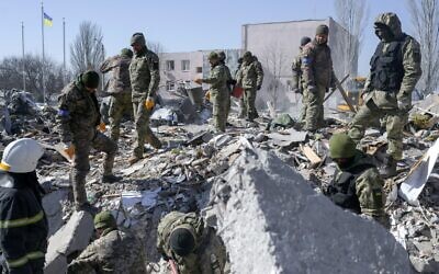 Ukrainian soldiers search for bodies in the debris at the military school hit by Russian rockets the day before, in Mykolaiv, southern Ukraine, on March 19, 2022. (Bulent Kilic/AFP)