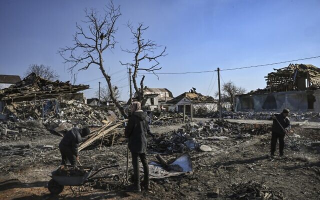 People clean up the debris from destroyed houses after bombardments in the village of Krasylivka, east of Kyiv, on March 20, 2022, as Russian forces try to encircle the Ukrainian capital. (Aris Messinis/AFP)