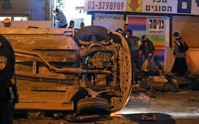 An overturned vehicle lies on the road at the scene of a terror attack on March 29, 2022 in Bnei Brak. - Five people were killed.  (Photo by GIL COHEN-MAGEN / AFP)