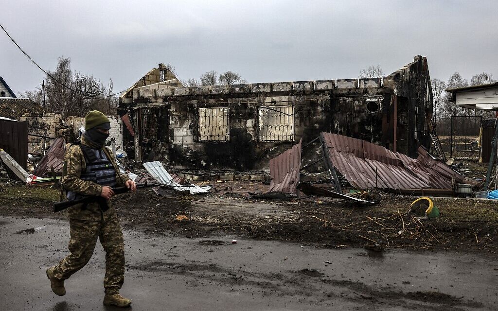 A Ukrainian soldier patrols next to a burned house in the village of Lukianivka near Kyiv on March 30, 2022. (RONALDO SCHEMIDT / AFP)