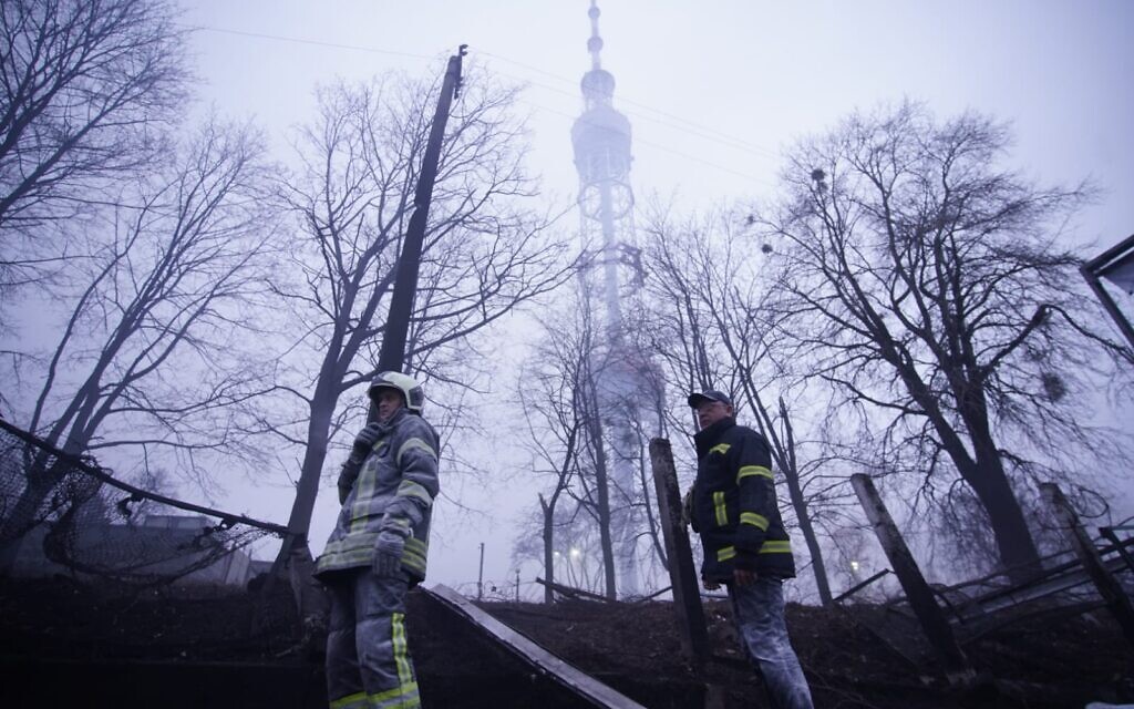 Ukrainian firefighters stand beneath a television broadcast tower in the Jewish cemetery located in Kyiv’s Babi Yar Holocaust memorial site, on March 1, 2022. (State Emergency Service of Ukraine)