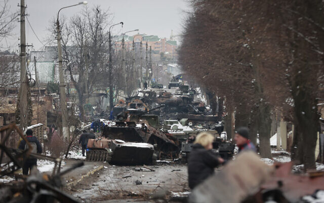 File -- People look at the gutted remains of Russian military vehicles on a road in the town of Bucha, close to the capital Kyiv, Ukraine, March 1, 2022 (AP Photo/Serhii Nuzhnenko)