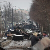 Illustrative: People look at the gutted remains of Russian military vehicles on a road in the town of Bucha, close to the capital Kyiv, Ukraine, Tuesday, March 1, 2022. (AP/Serhii Nuzhnenko)