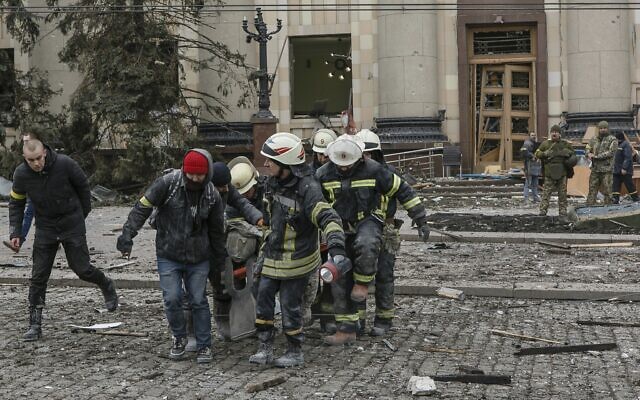 Ukrainian emergency service personnel carry a body of a victim out of the damaged City Hall building following shelling in Kharkiv, Ukraine, March 1, 2022. (AP/Pavel Dorogoy)