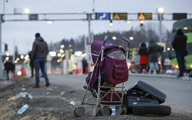 Deserted suitcase and a baby cart are left beside the road as Ukrainian refugees flee Russian invasion at a border crossing in Medyka, Poland, March 2, 2022. (AP Photo/Visar Kryeziu)