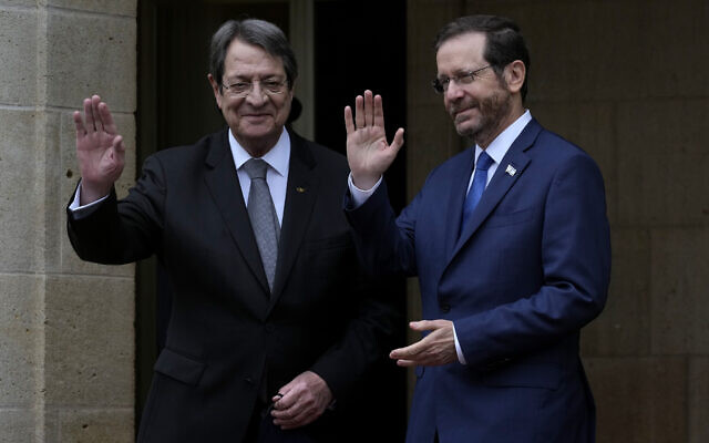 Cyprus' president Nicos Anastasiades, left, and Israeli President Isaac Herzog wave to the media before their meeting at the presidential palace in Nicosia, Cyprus, March 2, 2022. (AP Photo/Petros Karadjias)